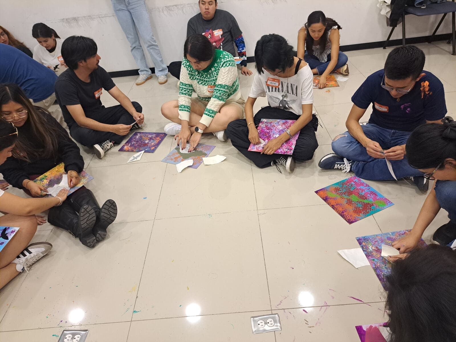 Grupo sentado en el piso pintando en un taller corporativo.